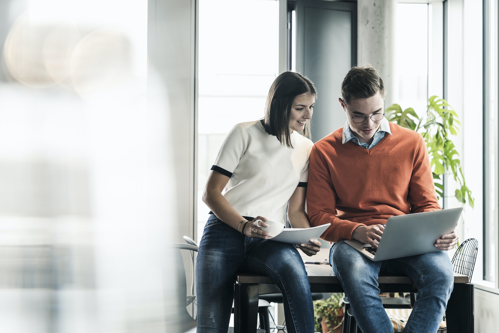 Casual businessman and woman with laptop meeting in office